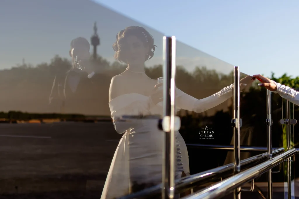 Mireasă cu un pahar de șampanie, portret artistic cu reflexie în sticlă, fotografie creativă de nuntă realizată de Ștefan Chelmu.