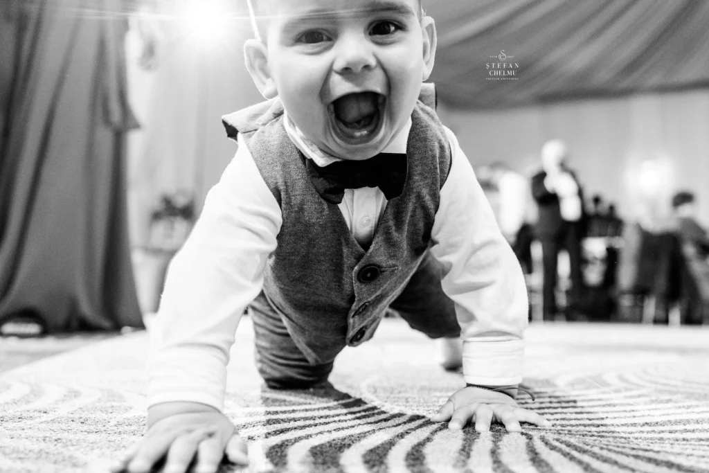 Copil vesel pe ringul de dans la o recepție de nuntă, imagine fotojurnalistica spontană alb-negru realizată de Ștefan Chelmu.