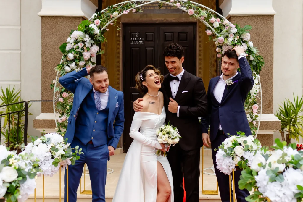 Mire, mireasă și cavaleri de onoare râzând cu gura până la urechi sub o arcadă florală, nuntă fără stres în Galați-Romania