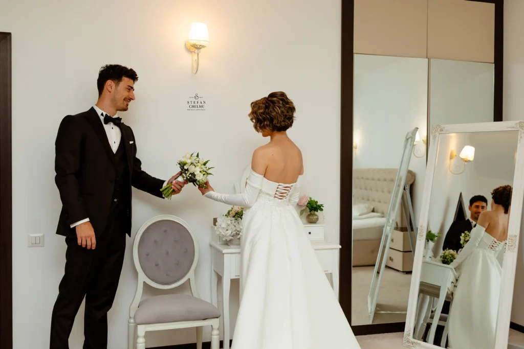 Mire dăruind buchetul miresei în fața oglinzii, reflexie completă, fotografie de nuntă Ștefan Chelmu.